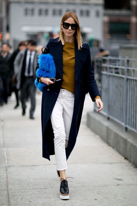 Blonde model styled in long coat and white pants
