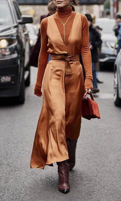 Model styled in a lowcut copper dress with a brown turtleneck underneath