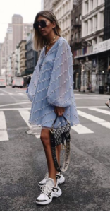 Caucasian model wearing a blue dress and white sneakers with black stripes