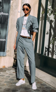 White female model styled in grey jacket and grey pants with white sneakers