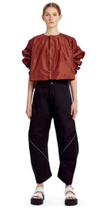Female model styled in puffy copper shirt and high-waisted black pants