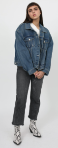 Brunette female model wearing oversized denim jacket with grey pants