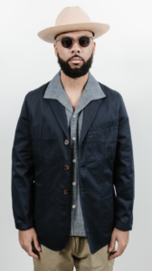 Black male model styled a dark blue jacket with a fedora