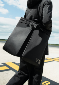 Model wearing all black carrying large black purse