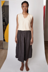 Black model styled in white cashmere shirt and a long dark grey skirt