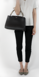 Model styled in white shirt and black pants holding a black purse