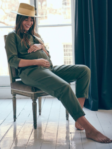 Pregnant woman styled in maternity clothes with a fedora