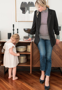 Blonde woman dressed business casual looking at little girl in white dress