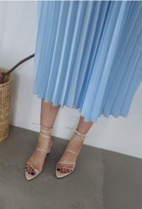 Woman wearing white sandals with thin straps around her ankles